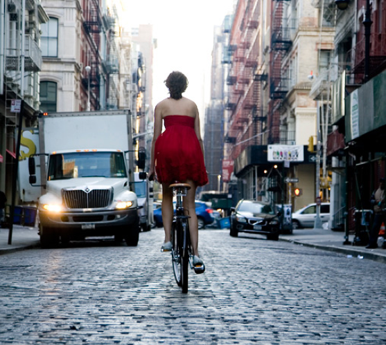 Girl is riding a bike on cobblestones street